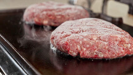Closeup shot of steam coming from grilling hamburger patties. Cooking at home, kitchen appliance, healthy nutrition, hamburger ingredients.