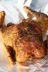 Whole roat chicken, covered in rosemary, on aluminium kitchen foil. Traditional Sunday roast concept