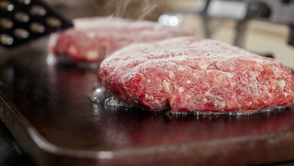 Closeup of juice flowing and boiling from hamburger patties. Cooking at home, kitchen appliance, healthy nutrition, hamburger ingredients.