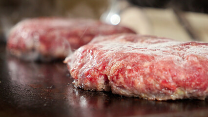 Macro shot of electric grill with frying burger patties being closed. Cooking at home, kitchen appliance, healthy nutrition, hamburger ingredients.