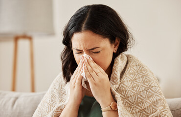 Nose, tissue and sick woman sneezing on a sofa with allergy, cold or flu in her home. Hay fever,...