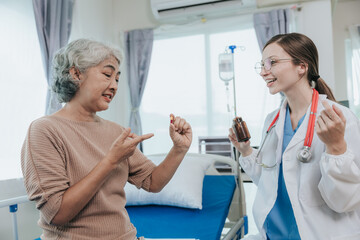 Friendly female doctor giving advice to elderly female Asian patient. Holding pill bottle.