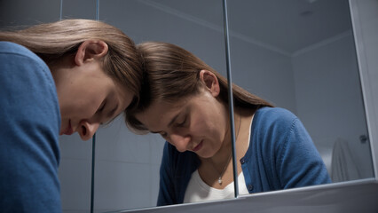 Portrait of angry and stressed woman leaning on mirror and looking in reflection. Concept of depression, suicide, stress, mental illness, loneliness and frustration.