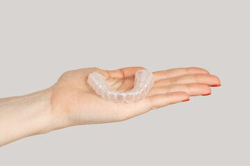 Closeup of woman hand showing invisible orthodontics cosmetic aligners. Indoor studio shot isolated...