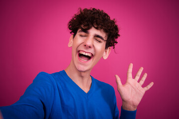Handsome emotional guy posing in the studio on a pink background.