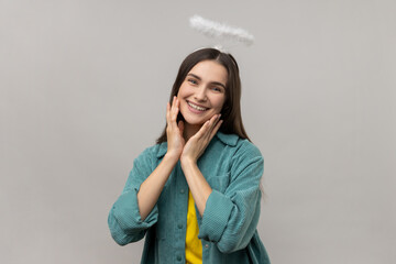 Attractive angelic woman with nimb over head, looking at camera with dreamy facial expression,...