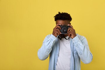 Professional black photographer in a long-sleeved shirt looks into the camera lens. A popular...