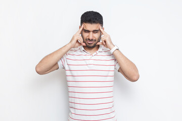 Portrait of sick unhealthy ill bearded man wearing striped t-shirt standing suffering headache,...