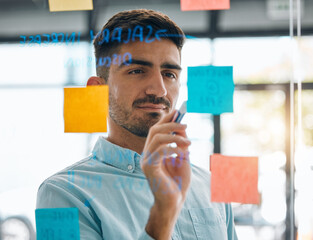 Business man brainstorming on glass, planning schedule and timeline of sticky note ideas. Face,...