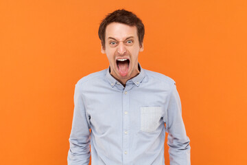 Portrait of crazy funny man standing with widely open mouth and sticking tongue out, looking at...