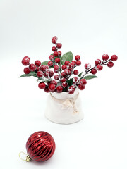 New Year's still life, a vase with red berries in the snow on a white background and a Christmas ball, a place for text