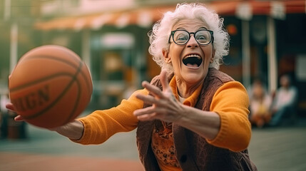 Elderly attractive woman with a happy expression on face throws the ball into the basketball ring on the basketball court in the city