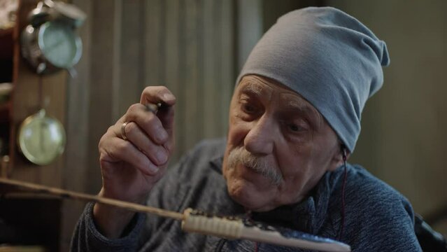 Elderly male master works in his workshop restoring japanese deba knife sheath