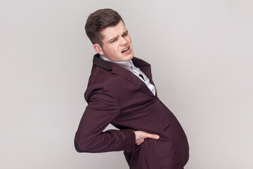 Portrait of frustrated anxious unhealthy man holding hands on lower back, kidney injury, backache,...