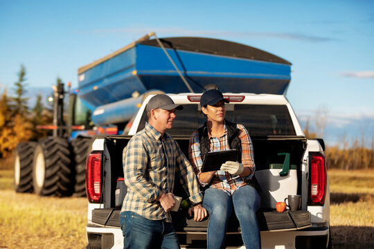 Farm couple uses tablet to monitor fall canola harvest while taking a coffee break, Alberta, Canada