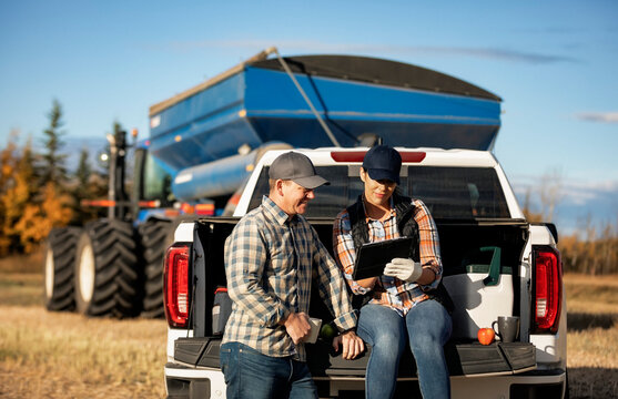 Farm couple uses tablet to monitor fall canola harvest while taking a coffee break, Alberta, Canada