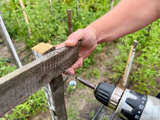 Obraz premium Worker drills screws in wooden construction in garden