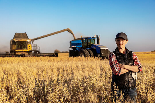 Portrait of a mature farm woman standing in a grain field during harvest at sunset, Alberta, Canada