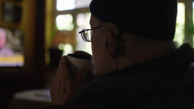 Old man in a wheelchair watching tv in the livingroom at home