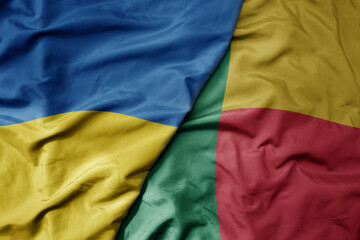 big waving national colorful flag of ukraine and national flag of benin