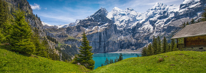 Amazing tourquise Oeschinnensee with waterfalls, wooden chalet and Swiss Alps, Berner Oberland, Switzerland.