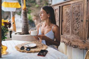 Female digital nomad drinking coffee in cafe