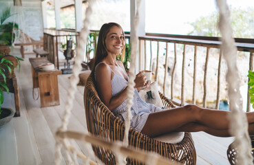 Happy woman with cup of coffee in cafe at resort