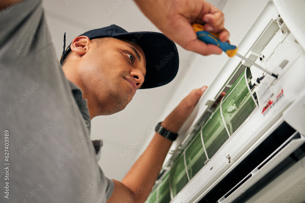 Poster Maintenance, air conditioner and man with screwdriver for problem solving on machine from below. Aircon, ac repair and handyman service with technician, electrician or contractor work on ventilation