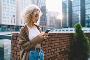 Positive young woman listening to music at city street