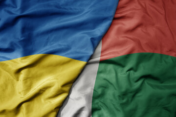 big waving national colorful flag of ukraine and national flag of madagascar .