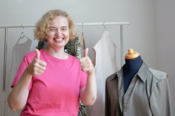 Woman fashion blogger showing modern woman clothing, clothes rack, large wardrobe with different clothes, home stuff, choice of clothes in the closet, sewing workshop