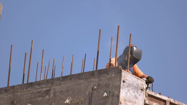 Welder with mask working on the construction site. Blue sky ibb the background.