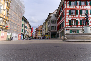 Alley at the medieval old town of City of Winterthur with colorful facades of historic houses and fountain on a cloudy spring day. Photo taken May 17th, 2023, Winterthur, Switzerland.