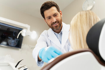 Handsome bearded dentist preparing female patient to checking teeth