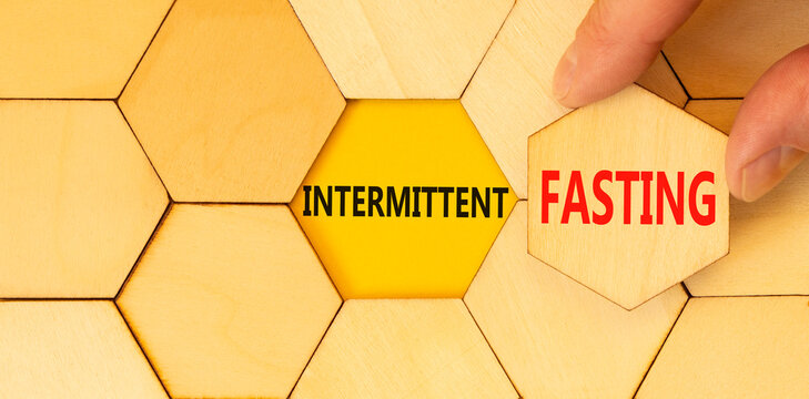 Intermittent fasting symbol. Concept words Intermittent fasting on beautiful wooden puzzles. Beautiful yellow background. Doctor hand. Healthy lifestyle intermittent fasting concept. Copy space.