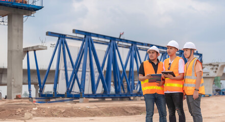 Group of asian engineers discuss about work at site of building under construction,The contractor team discusses the design of the structure,Three workers are working outside.