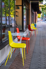 Blurred tables and chairs in the street. Colored chairs and tables, at outdoor coffee shop. Colored...