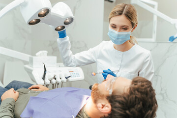 Professional woman dentist turning lamp while preparing checking man teeth