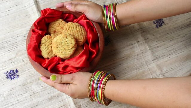 Thekua , an Indian sweet dish or a snacks in earthen pot holding by woman hand. Popular in bihar jharkhand. Prashad in chhath maha parv or puja or festival. selective focus.