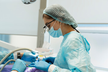 Cropped view of the surgeon with microscope during dental operation