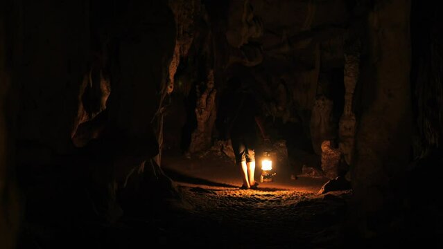 Tourist guide holding burning lantern and walking through Tham Lod cave - famous natural limestone cave system, Northern Thailand. High Quality 4K slowmotion travel nature exploring concept footage.