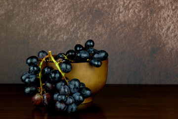 Small Wooden Bowl with Grapes on a Varnished Wooden Surface