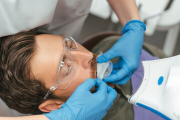Cropped view of dentist in latex gloves putting mouth guard to male patient