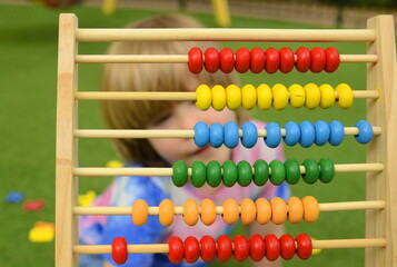 Little boy Boy learning to count beads on colorful wooden abacus. Close-up face. Mathematics for preschoolers. Learn numbers