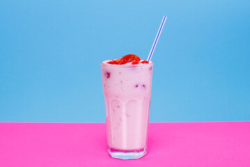 Glass of strawberry yogurt on colorful background. Strawberry yogurt on blue and pink background. Glass of strawberry yogurt covered by fresh strawberry slices. 