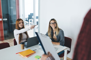 Cheerful women with laptop at table attending class room in office