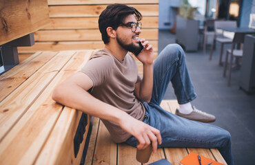 Young man resting and talking on smartphone in cafe