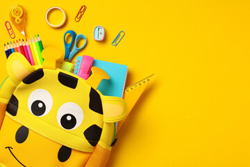 Giraffe backpack with colourful school supplies on yellow background. Back to school concept. Flat...