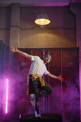 Obraz na płótnie Canvas Young guy hiphop performer break dancing in neon club lighting
