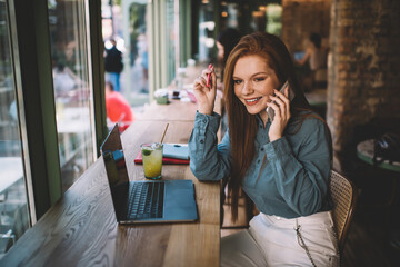 Smiling woman talking on smartphone in cafe